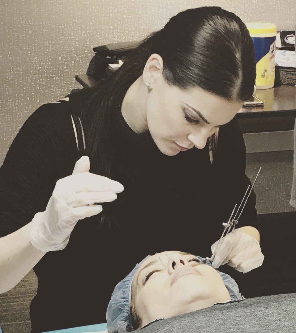 A Woman performing microblading on client's eyebrows
