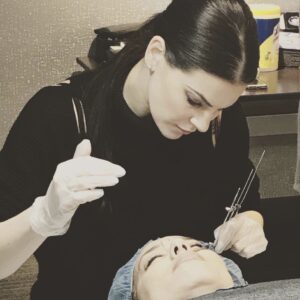 A Woman performing microblading on client's eyebrows